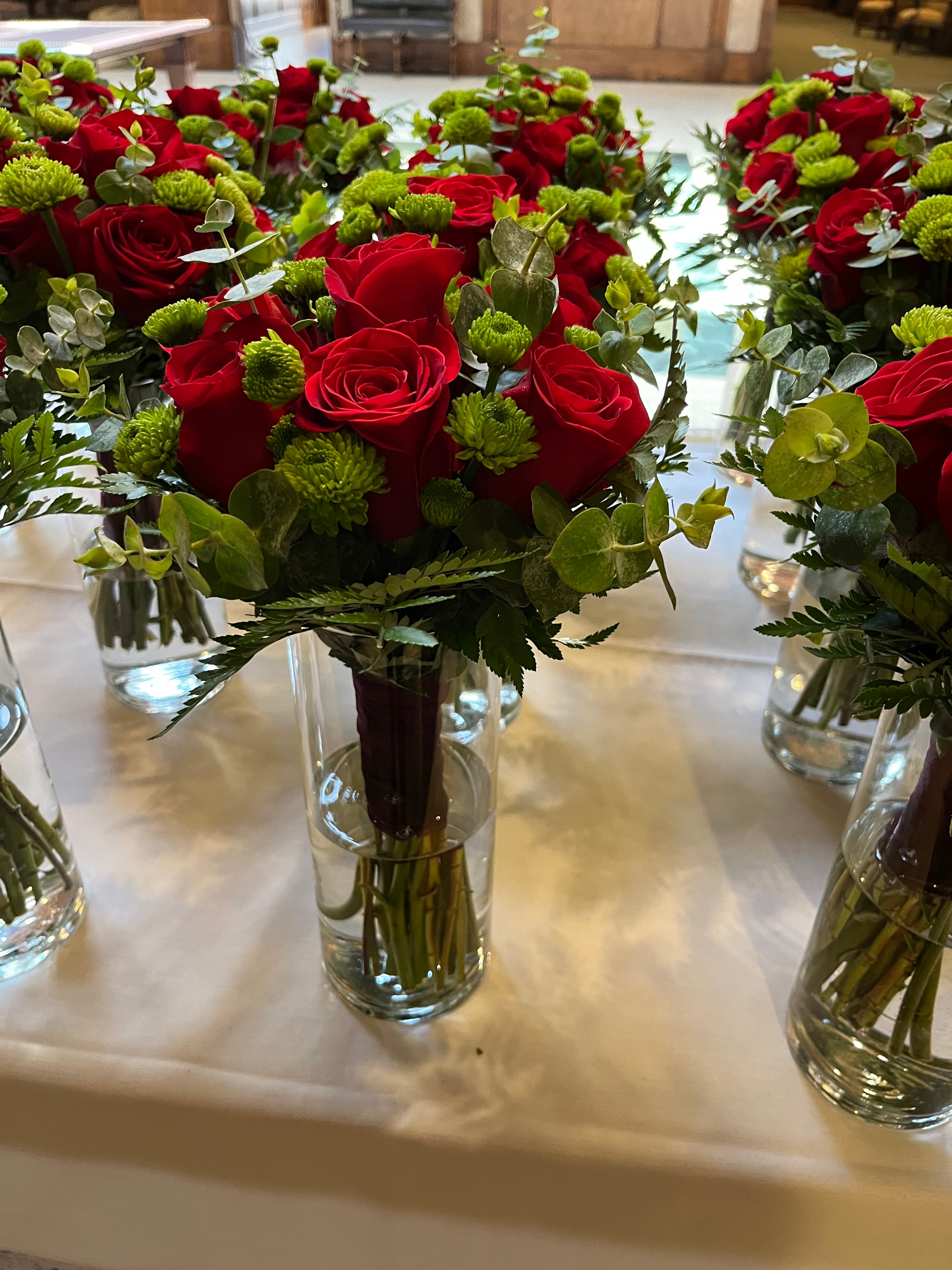 Red roses and green button mums garland with glass cylinder vases on banquet table
