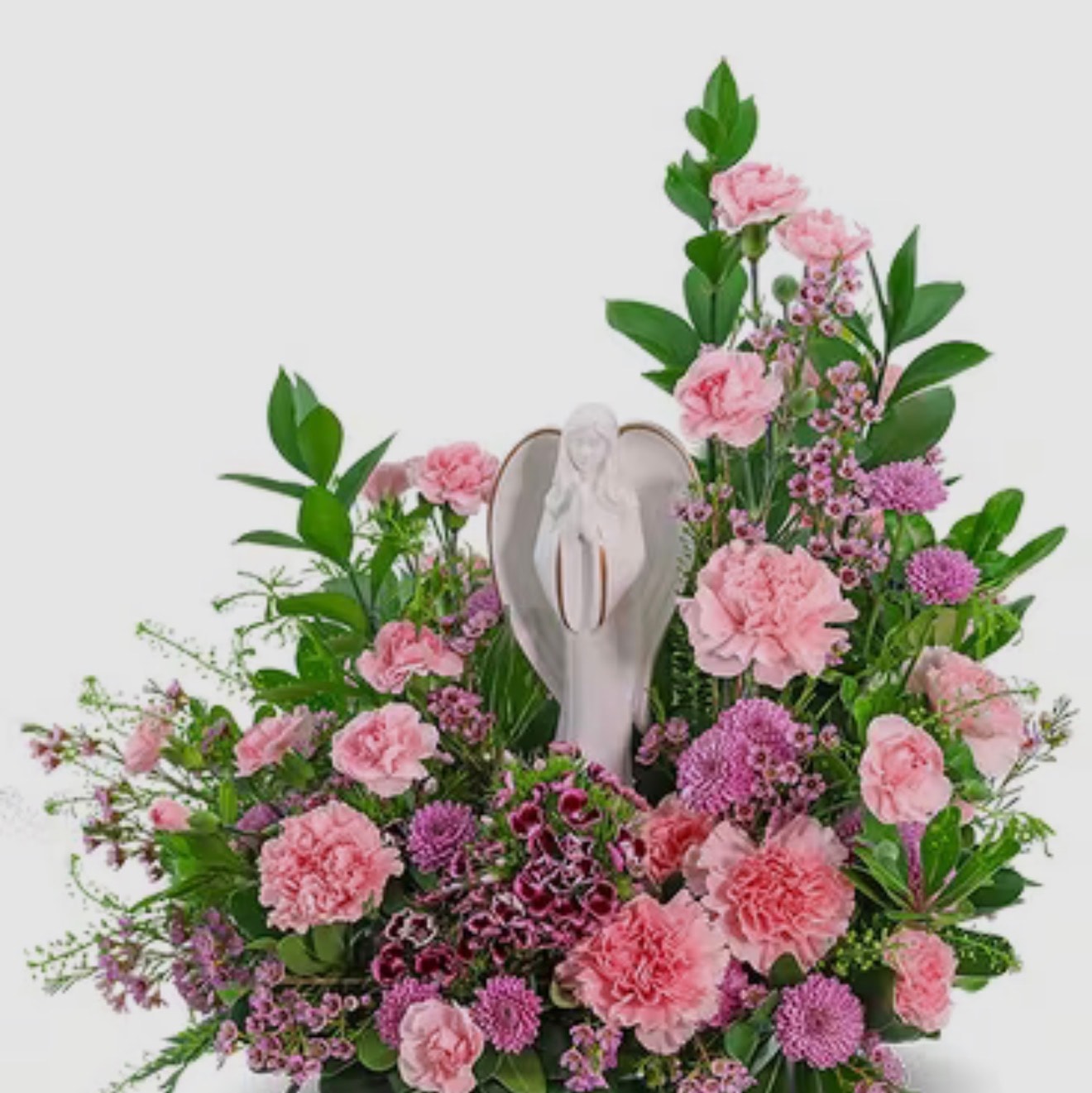 Pink carnation and purple mum arrangement surrounding white angel figurine keepsake
