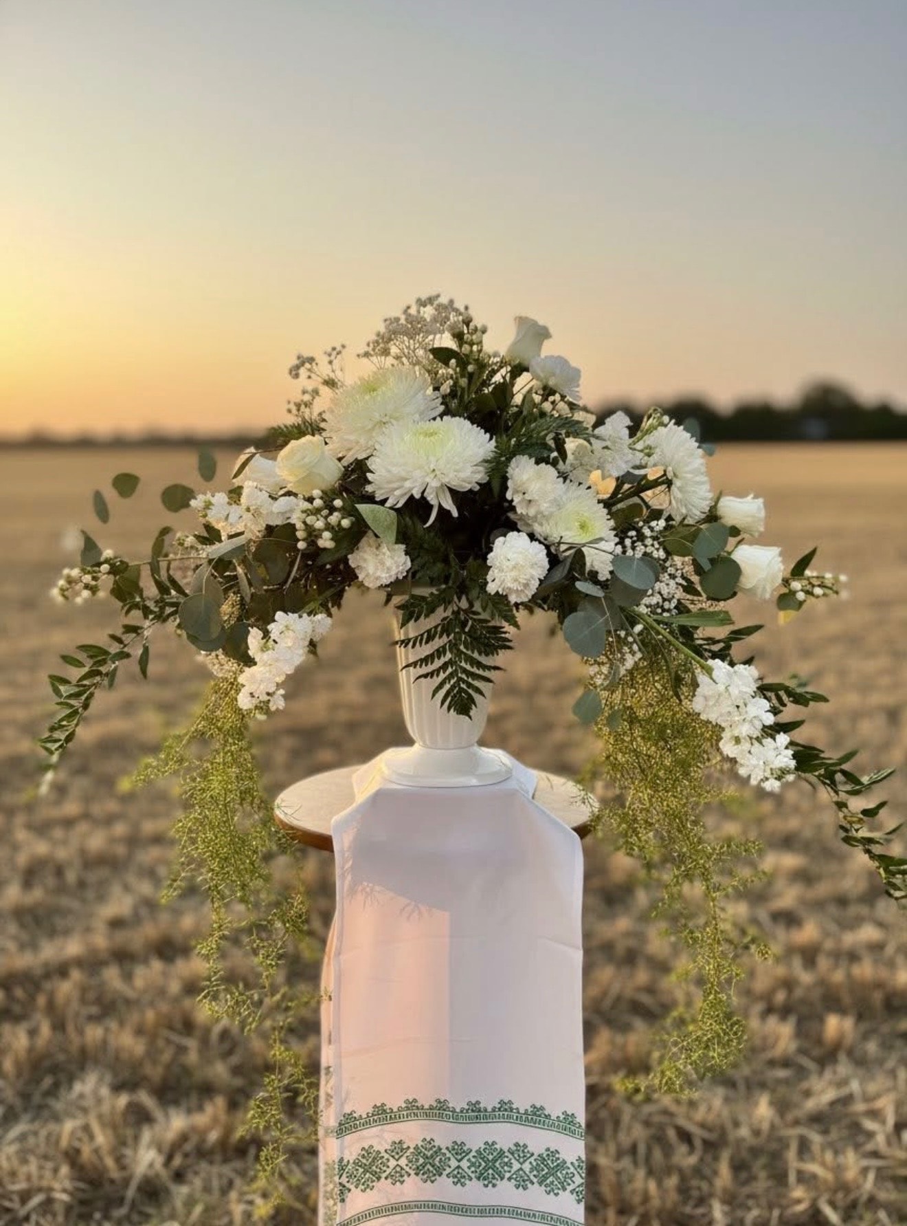 Peach rose and carnation urn arrangement with greenery