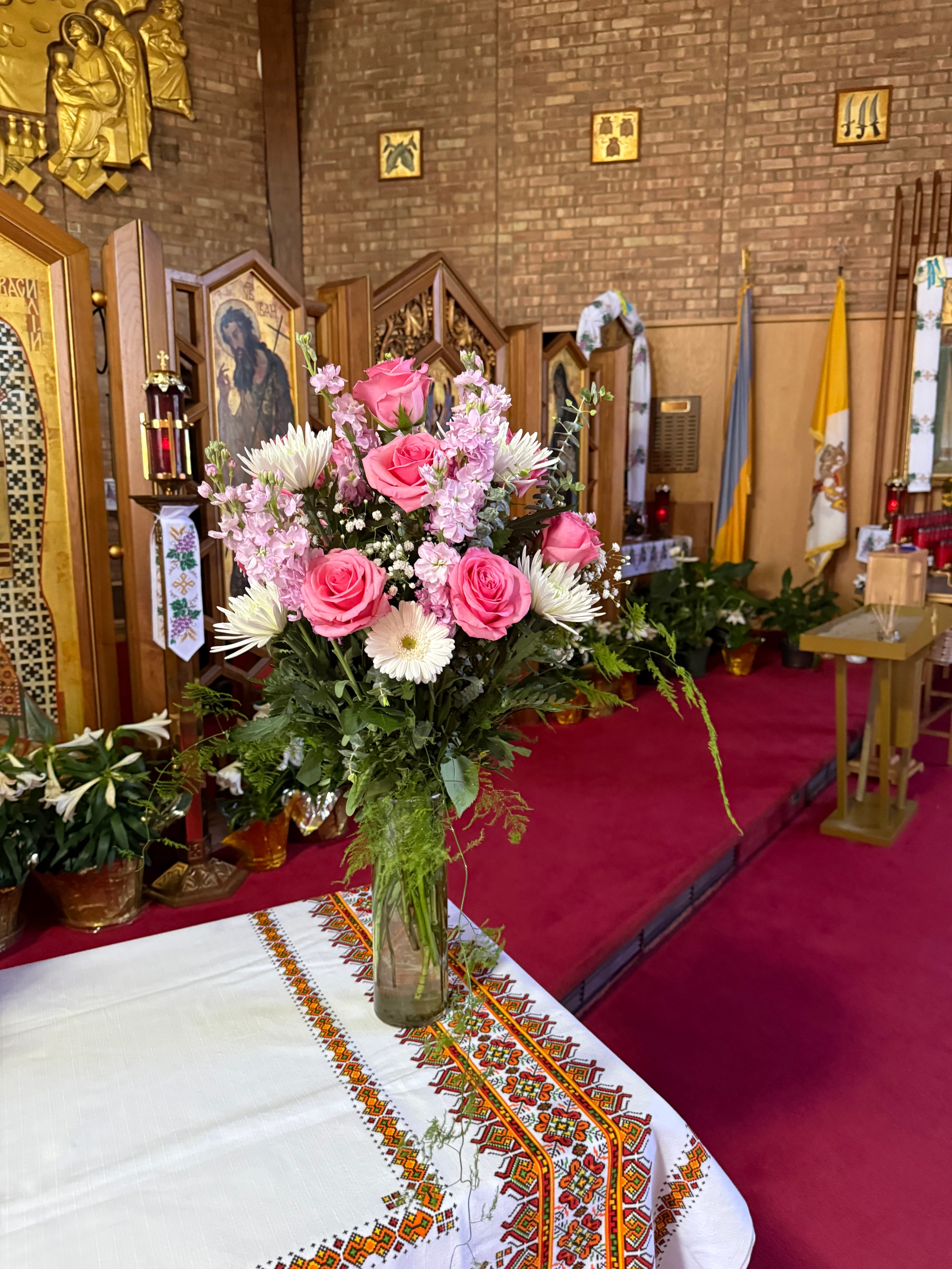 Pink roses, white daisies, and greenery in a vase
