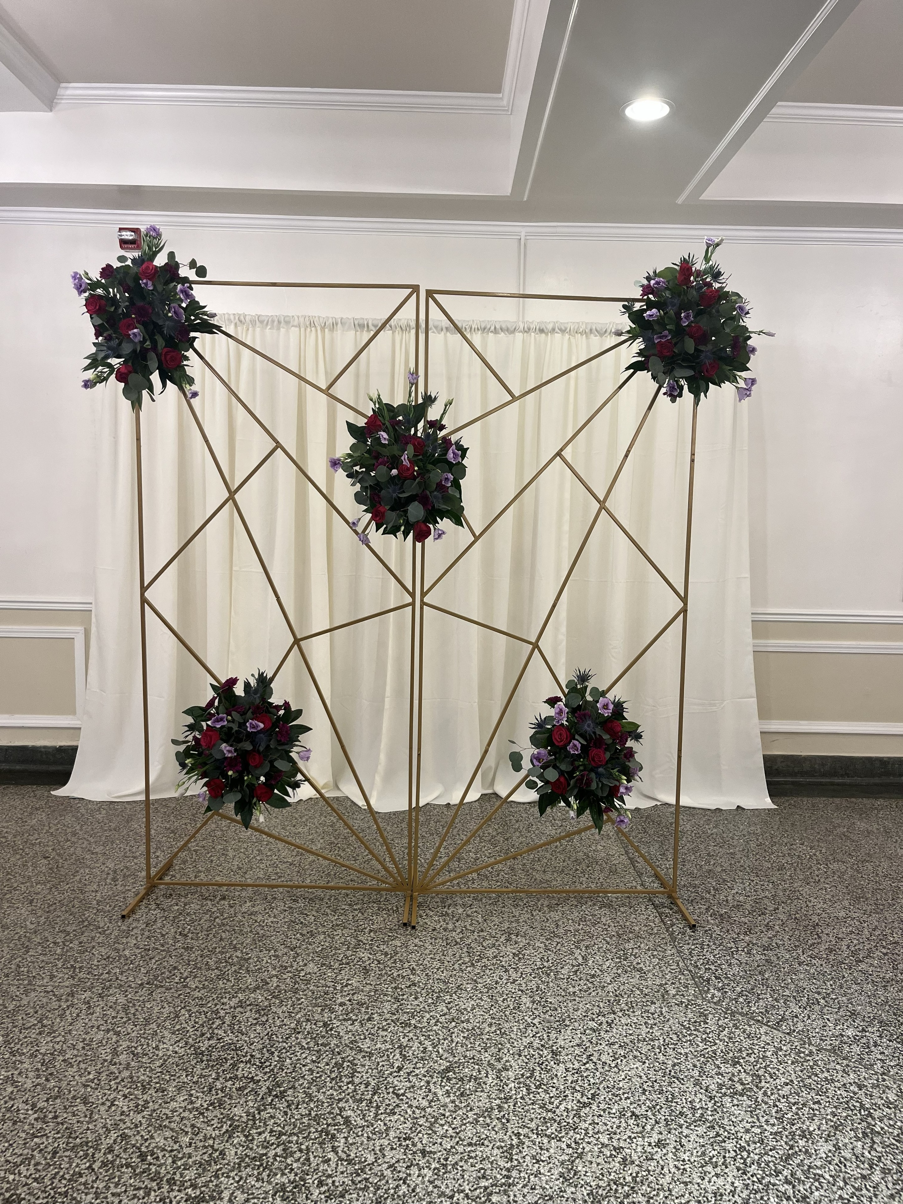 Geometric gold frame backdrop with burgundy and purple floral clusters